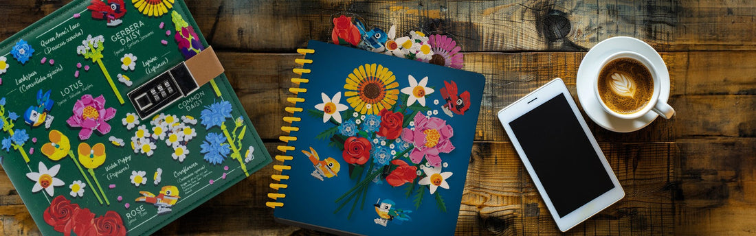 Two LEGO Botanicals notebooks on a wood table next to a phone and coffee cup.